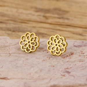 Detail of gold mandala flower stud earrings with intricate cutout petals on stone
