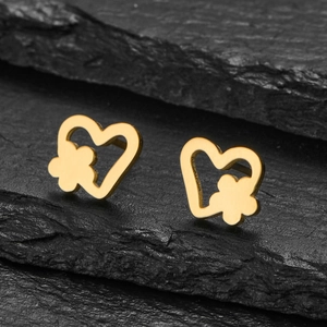 Close-up of gold heart-shaped stud earring with flower detail on black rock background