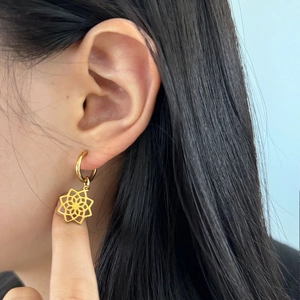Détail d'une boucle d'oreille dorée avec pendentif géométrique portée par un mannequin