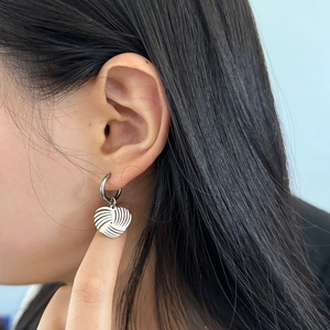 Gros plan de boucles d'oreilles cœur en acier inoxydable argenté sur un modèle