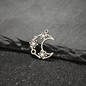 Detailed view of stainless steel crescent moon pendant with镂空 flower design on slate