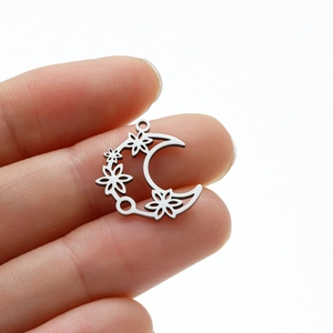 Detailed view of small crescent moon and flower stainless steel charms for DIY jewelry making