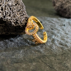 Luxe gold-plated heart key open ring with pavé pink zircons on dark volcanic stone background