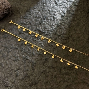 Macro shot of gold-plated titanium steel bracelets with mini clover and butterfly charms