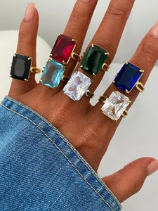Primo piano di sette anelli in zircone colorato con fasce oro e argento sulla mano