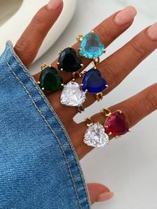 Primo piano di anelli d'oro con pietre a forma di cuore in colori vivaci su una mano