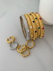 Detail of vintage gold and silver bracelets with brushed texture and colorful gemstones
