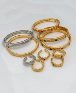 Macro view of brushed gold and silver bracelets with inlaid colorful gemstones