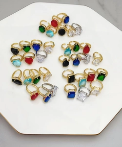 Dettaglio di anelli regolabili con pietre di zircone colorate a forma di cuore e goccia