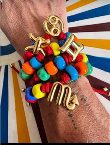 Detail of colorful beaded zodiac bracelets with golden metal charms on a wrist