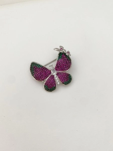Close-up of pavé butterfly brooch featuring purple and green zircon stones on silver base