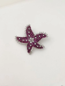 Détail d'une broche étoile de mer avec strass roses et blancs sur métal argenté