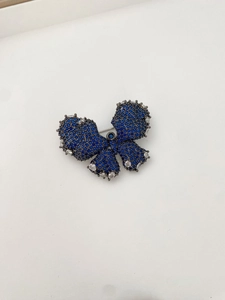 Macro shot of butterfly brooch with blue zircon inlay on dark vintage metal base