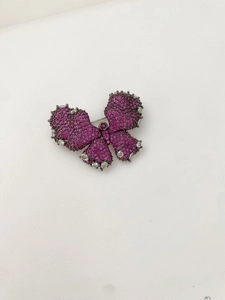 Detail view of butterfly brooch with magenta zircons and dark metal base