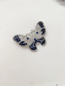 Detail of silver butterfly brooch with blue and white inlaid crystals and hollow design