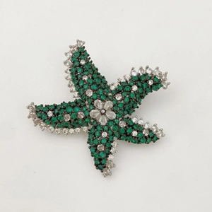 Élégante broche étoile de mer argentée avec cristaux verts et blancs sur blanc
