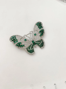 Detailed close-up of a butterfly brooch with sparkling green and white crystals