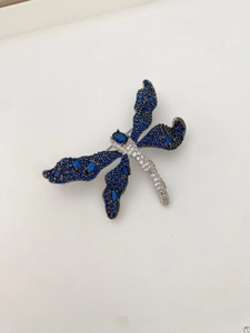 Macro shot of dragonfly brooch with blue zircons and intricate silver-tone wing details