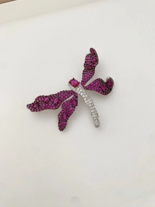 Macro shot of dragonfly brooch with pink wing stones and white crystals on silver base