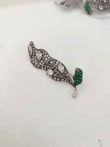 Vue détaillée de la broche feuille en argent avec zircons blancs et accents de gemmes vertes