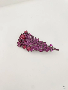 Macro shot of rose purple feather brooch with rhinestones on a dark metal base