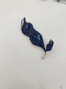 Détail macro de la broche feuille avec zircons bleus et monture en métal argenté