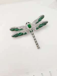 Détail macro d'une broche libellule avec pierres vert émeraude et pavé d'oxydes de zirconium