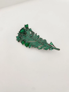Macro shot of vintage emerald feather brooch with green crystals and dark metal details
