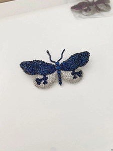 Détail de la broche papillon avec micro-pavage de zircons bleus et blancs de luxe