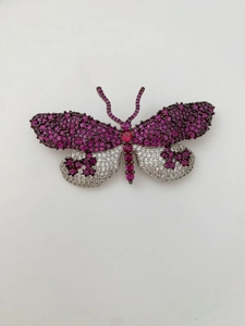 Détail de la broche papillon avec pierres précieuses violettes et blanches sur métal noir