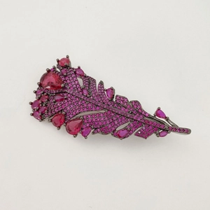 Elegant feather brooch featuring dark metal set with pink crystals and emerald stones