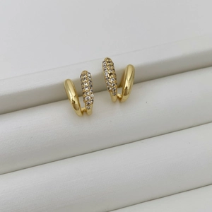 Detailed macro view of gold-plated C-shaped earrings with micro-pave cubic zirconia crystals