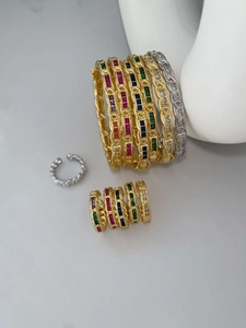Detail view of gold and silver chain bracelets with vibrant square-cut zircons set on ceramic