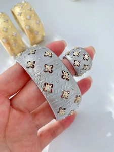 Dettaglio del set bracciale e anello a fiore in metallo spazzolato con piccoli diamanti