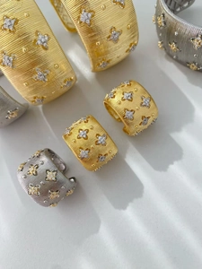 Dettaglio macro della texture spazzolata oro 18K con incastonatura a stella e diamanti