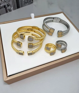 Gros plan de bracelets torsadés dorés et gris avec extrémités carrées en zircon
