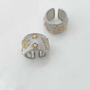 Detailed macro of wide silver-toned rings with brushed finish and colorful butterfly gems