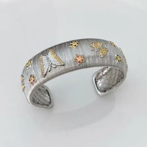 Detail of brushed silver cuff bangle with colorful zircon butterfly and floral inlays