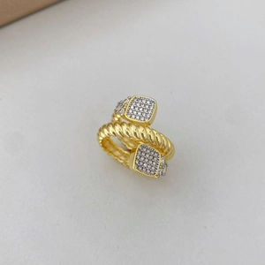 Gros plan sur une bague torsadée dorée avec extrémités carrées et pavage de zircons