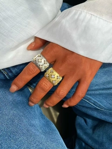 Dettaglio macro di anelli in oro e argento satinato con accenti floreali e diamanti
