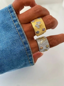Detail showing gold and silver brushed metal rings with cubic zirconia butterfly patterns