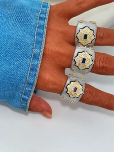 Detail view of brushed silver and gold rings with emerald, blue, and ruby gemstones