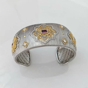 Detailed view of Italian-style brushed silver cuff with golden floral design and red gemstone