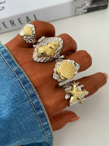Detail of 18k gold plated ocean rings with starfish and shell on hand with hammer texture