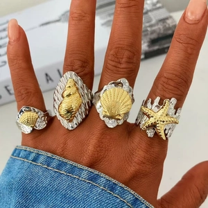 Marine 18k gold duo-tone ocean rings set with seashell and starfish on hand