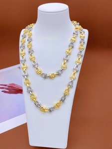 Close-up of two-tone gold and silver metal chain links on a mannequin neck