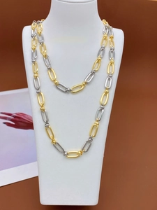 Detail of minimalist gold and silver two-tone chain necklace on a white bust