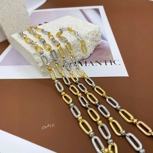 Two-tone gold and silver oval link chain necklace with metal beads on textured stone