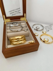 Macro shot of 18k gold plated wave bangles and rings inside a luxury wooden jewelry box