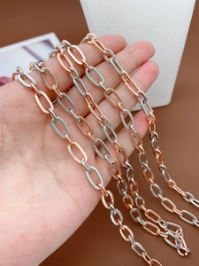 Detail of mixed silver and rose gold paperclip chain held by a hand on a stand